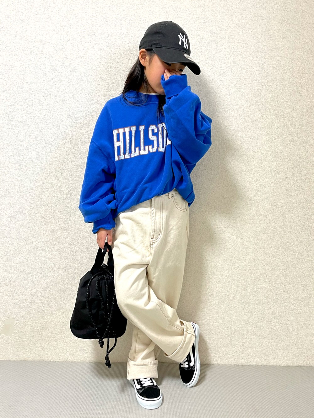 ブルー系のスウェット、ブラック系のショルダーバッグ、ベージュ系のデニムパンツを着用したキッズの冬コーディネートの2枚目の写真