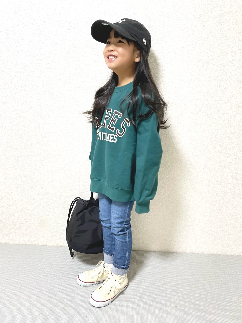グリーン系のスウェット、ブルー系のデニムパンツ、ホワイト系のスニーカーを着用したキッズの冬コーディネートの2枚目の写真