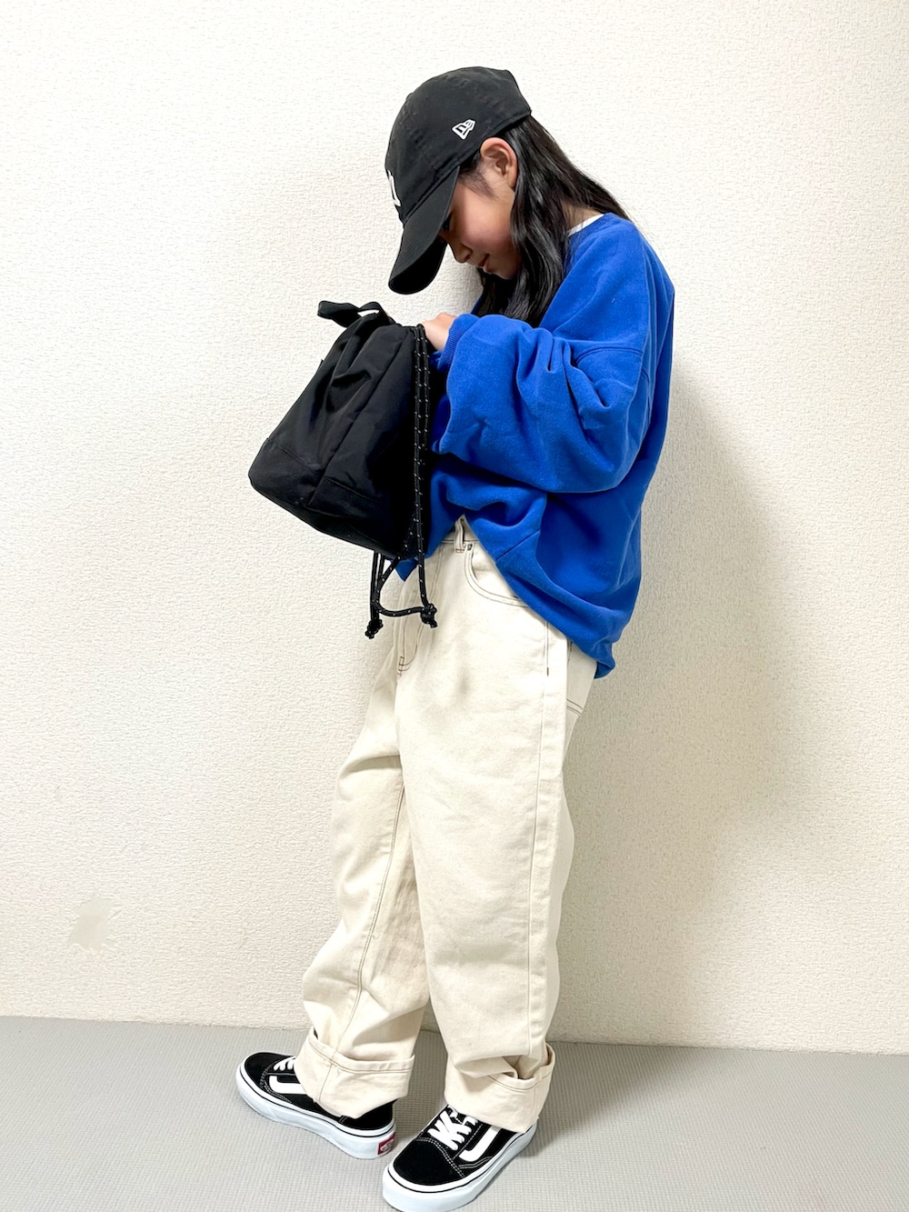 ブルー系のスウェット、ブラック系のショルダーバッグ、ベージュ系のデニムパンツを着用したキッズの冬コーディネートの3枚目の写真