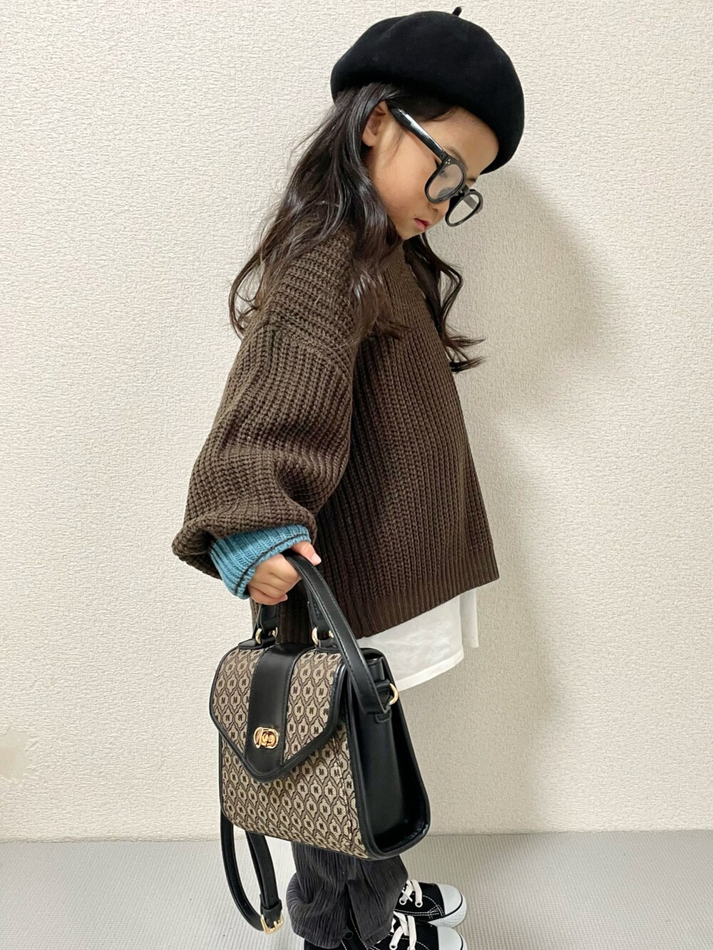 ブラウン系のニット/セーター、ブラック系のスニーカー、ブラウン系のショルダーバッグを着用したキッズの冬コーディネートの3枚目の写真