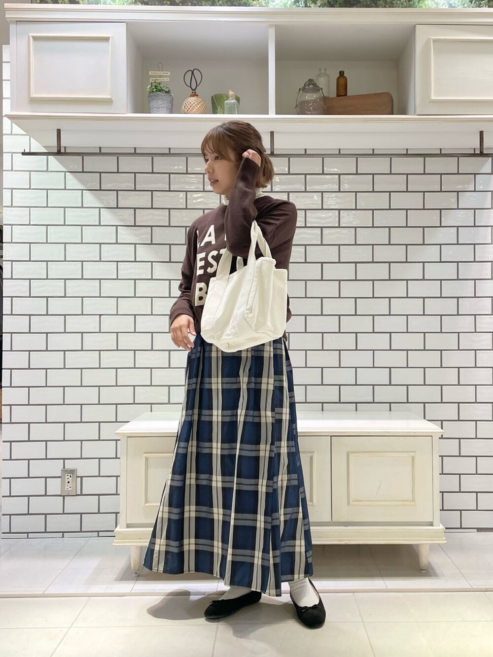 ブラウン系のニット/セーター、イエロー系のワンピース、ブラック系のパンプスを着用したレディースの秋コーディネートの2枚目の写真