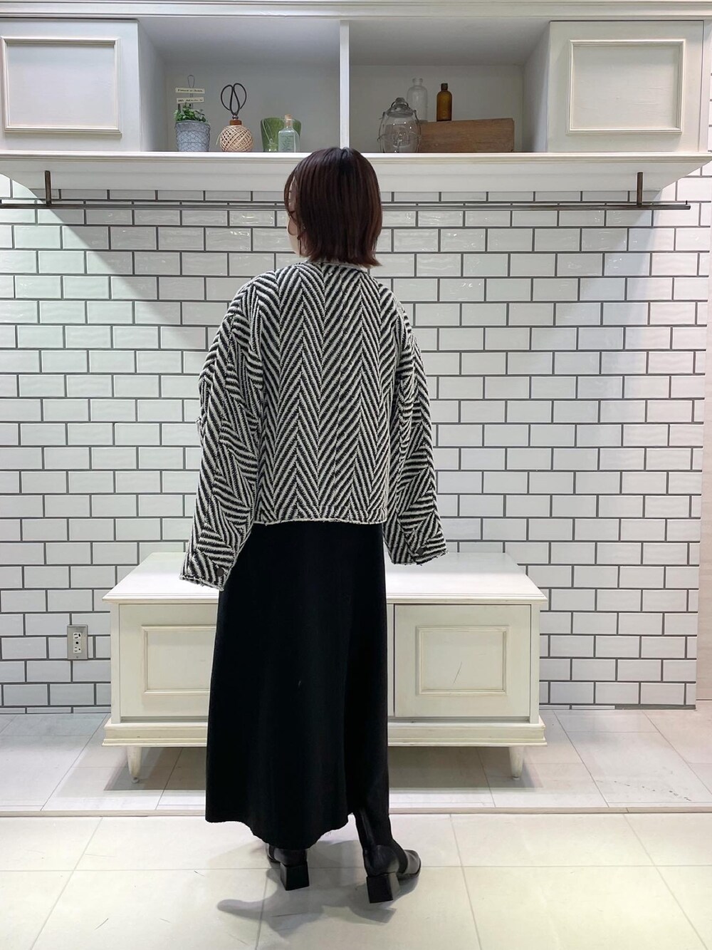 ホワイト系のニット/セーター、グレー系のジャンパースカート、ブラック系のショルダーバッグを着用したレディースの冬コーディネートの3枚目の写真