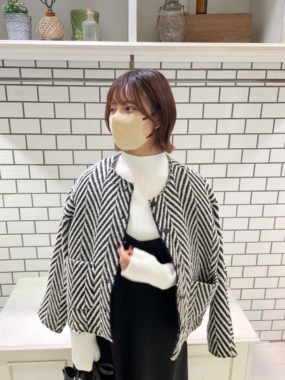 ホワイト系のニット/セーター、グレー系のジャンパースカート、ブラック系のショルダーバッグを着用したレディースの冬コーディネートの4枚目の写真