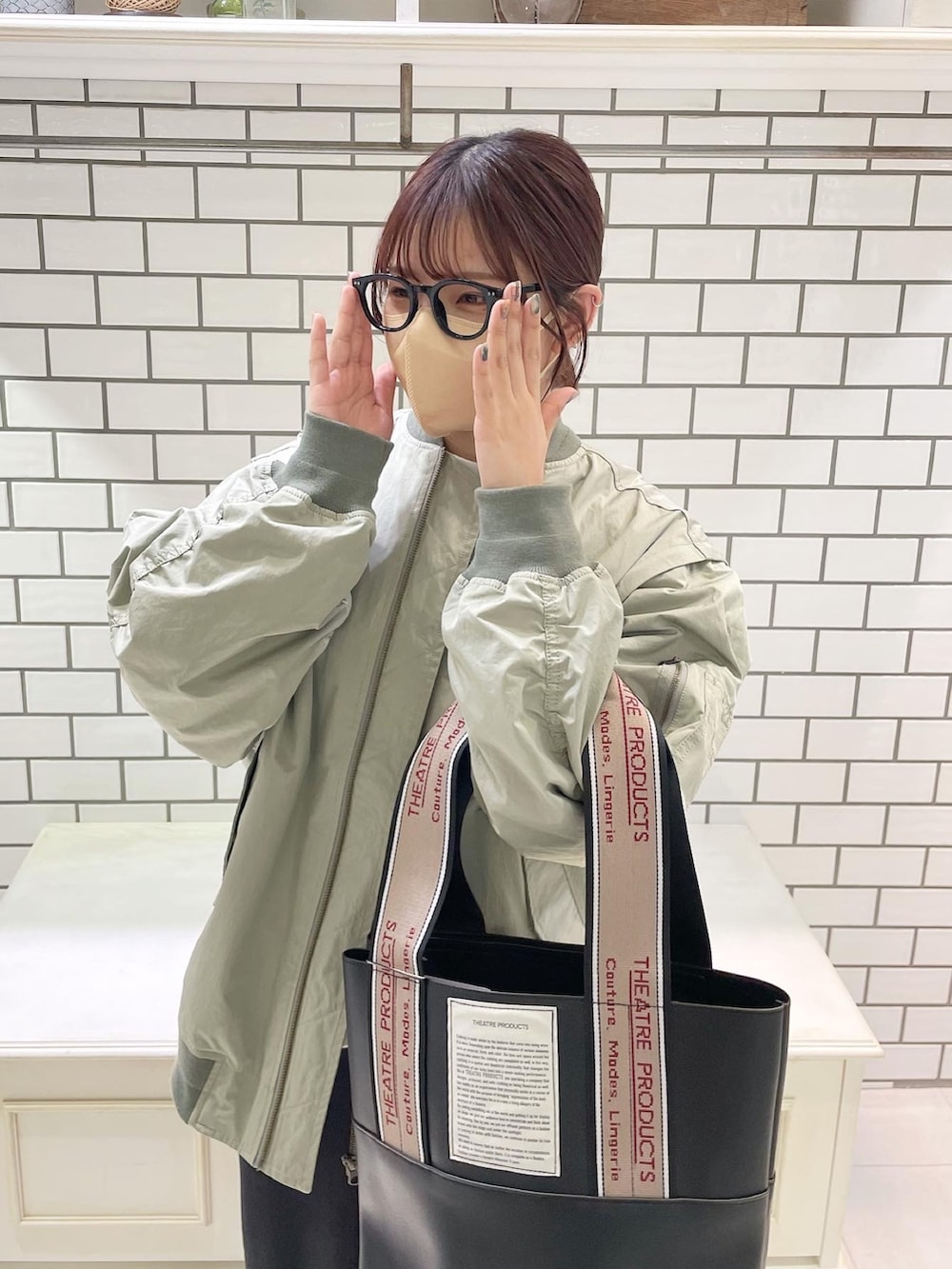 グリーン系のMA-1、ブラック系のトートバッグ、ブラック系のスカートを着用したレディースの冬コーディネートの3枚目の写真