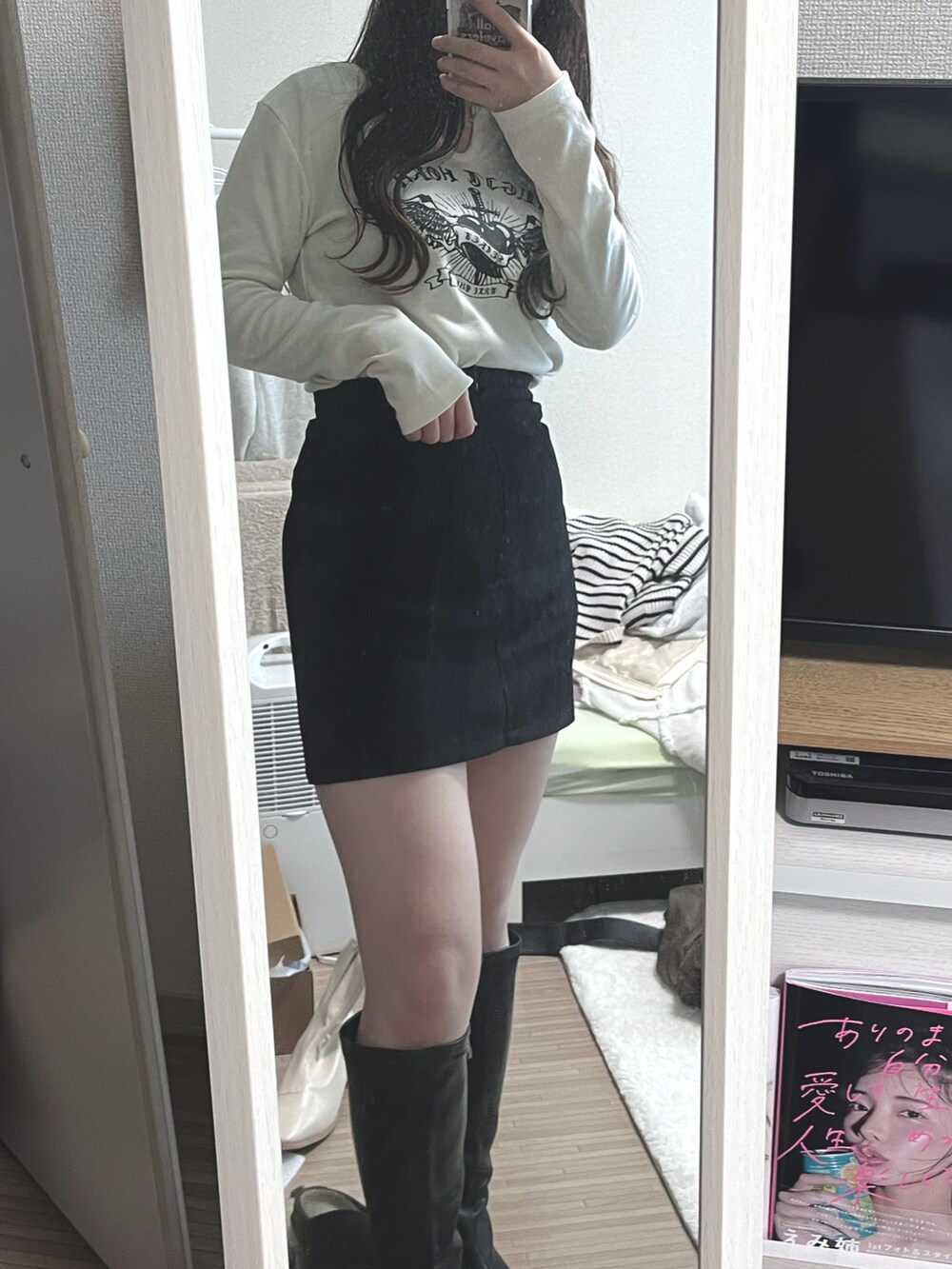 ブラック系のスカート、ホワイト系のダウンベスト、ブラック系のショルダーバッグを着用したレディースの冬コーディネートの2枚目の写真