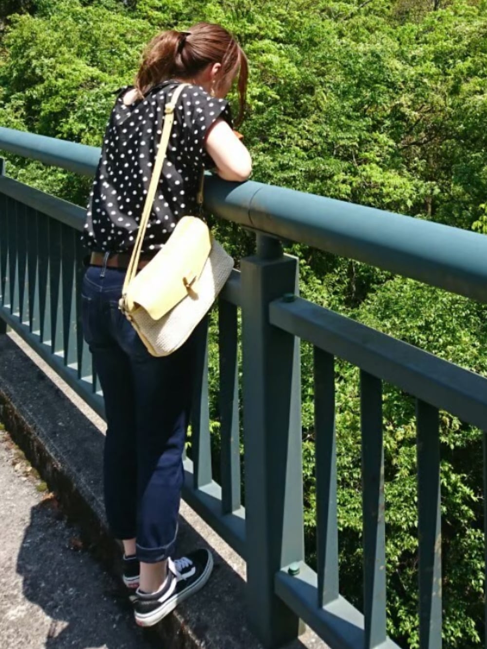 ブルー系のデニムパンツ、イエロー系のショルダーバッグ、ブラック系のスニーカーを着用したレディースの夏コーディネートの2枚目の写真