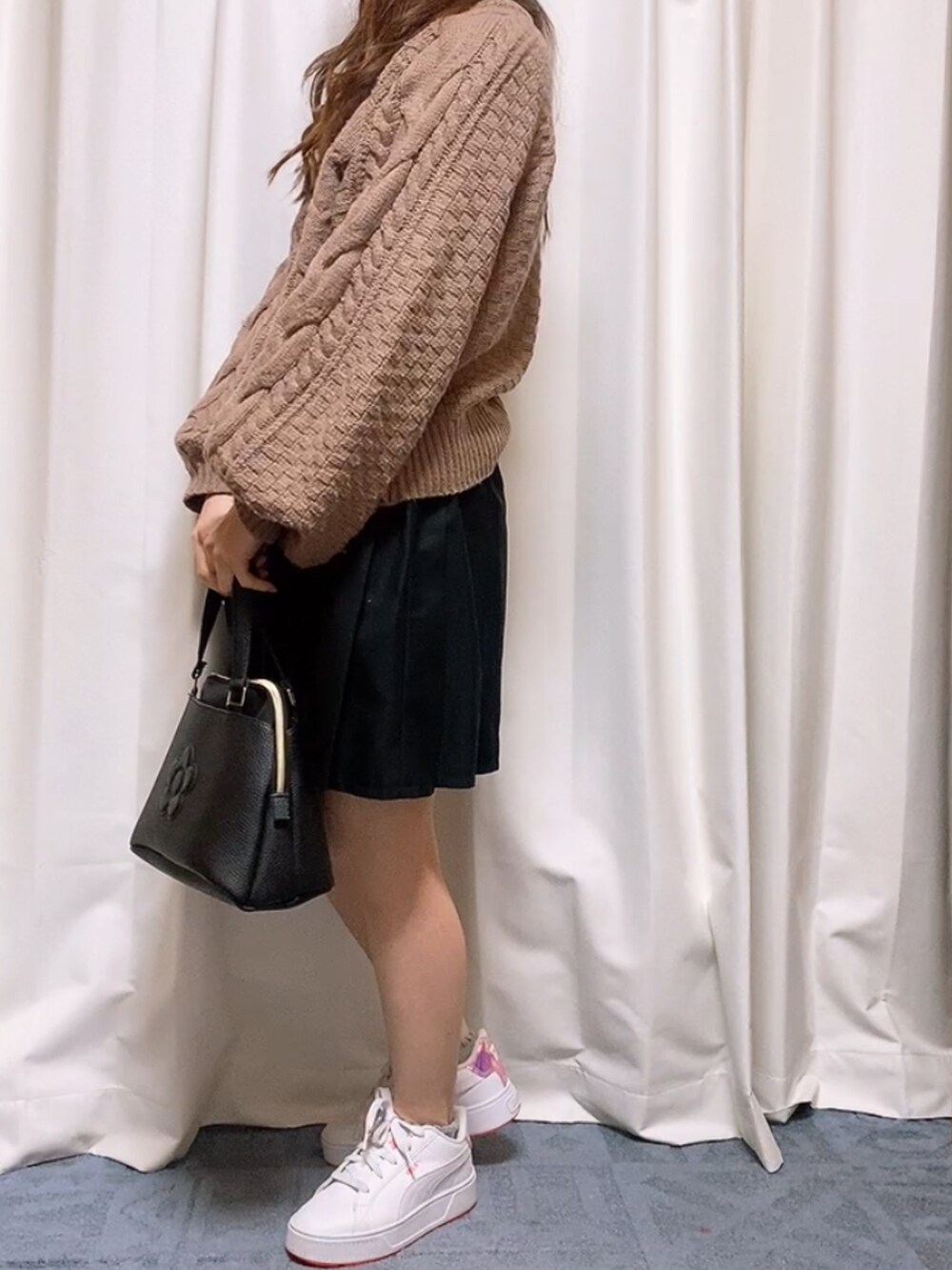 ピンク系のニット/セーター、ブラック系のスカート、ホワイト系のスニーカーを着用したレディースの春コーディネートの3枚目の写真