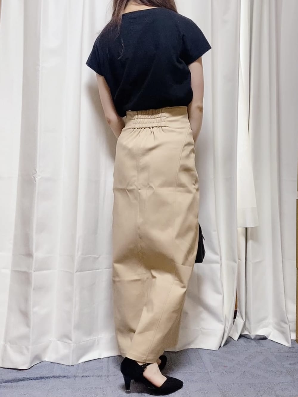 ブラック系のTシャツ/カットソー、ブラック系のハンドバッグ、ベージュ系のスカートを着用したレディースの夏コーディネートの2枚目の写真