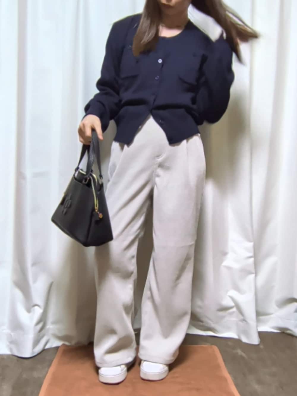 ホワイト系のパンツ、ブラック系のバッグ、ブルー系のカーディガン/ボレロを着用したレディースの春コーディネートの2枚目の写真