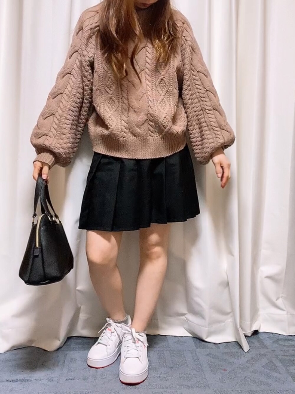 ピンク系のニット/セーター、ブラック系のスカート、ホワイト系のスニーカーを着用したレディースの春コーディネートの2枚目の写真