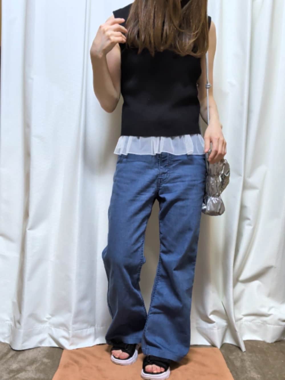 ブルー系のデニムパンツ、ブラック系のサンダル、シルバー系のショルダーバッグを着用したレディースの夏コーディネートの2枚目の写真