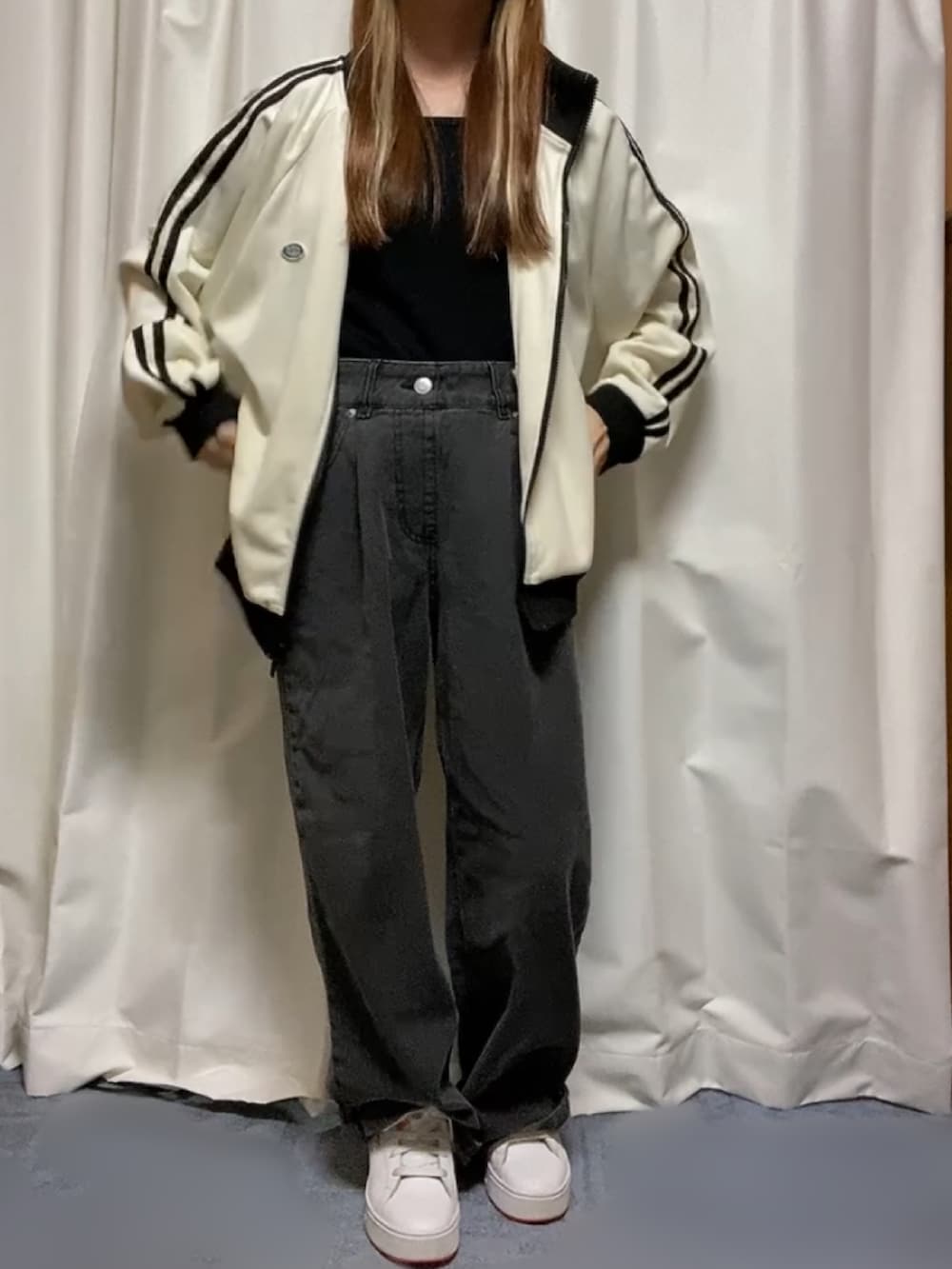ホワイト系のブルゾン、ブラック系のデニムパンツ、ホワイト系のスニーカーを着用したレディースの秋コーディネートの2枚目の写真