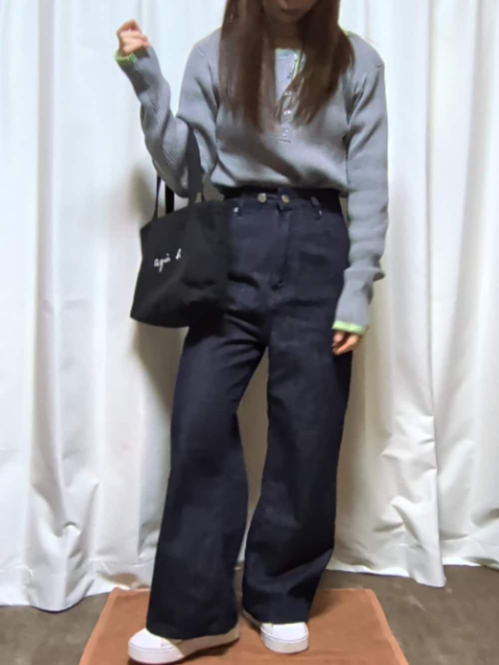 グレー系のトップス、ブラック系のバッグ、ブルー系のデニムパンツを着用したレディースの春コーディネートの2枚目の写真