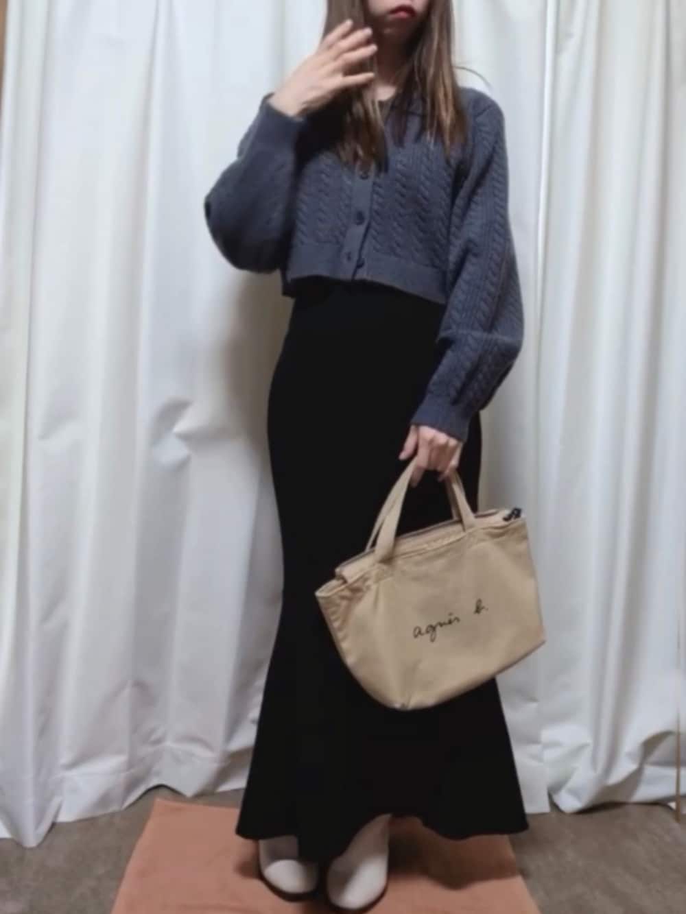ベージュ系のバッグ、ブルー系のニット/セーター、ブラック系のスカートを着用したレディースの秋コーディネートの2枚目の写真