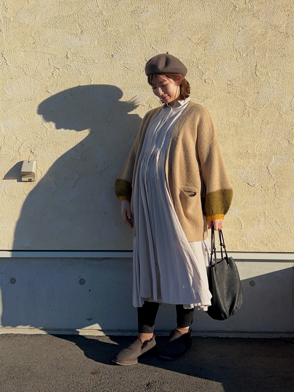 ブラウン系のスリッポン、ブラック系のハンドバッグ、ベージュ系のカーディガン/ボレロを着用したレディースの冬コーディネートの2枚目の写真