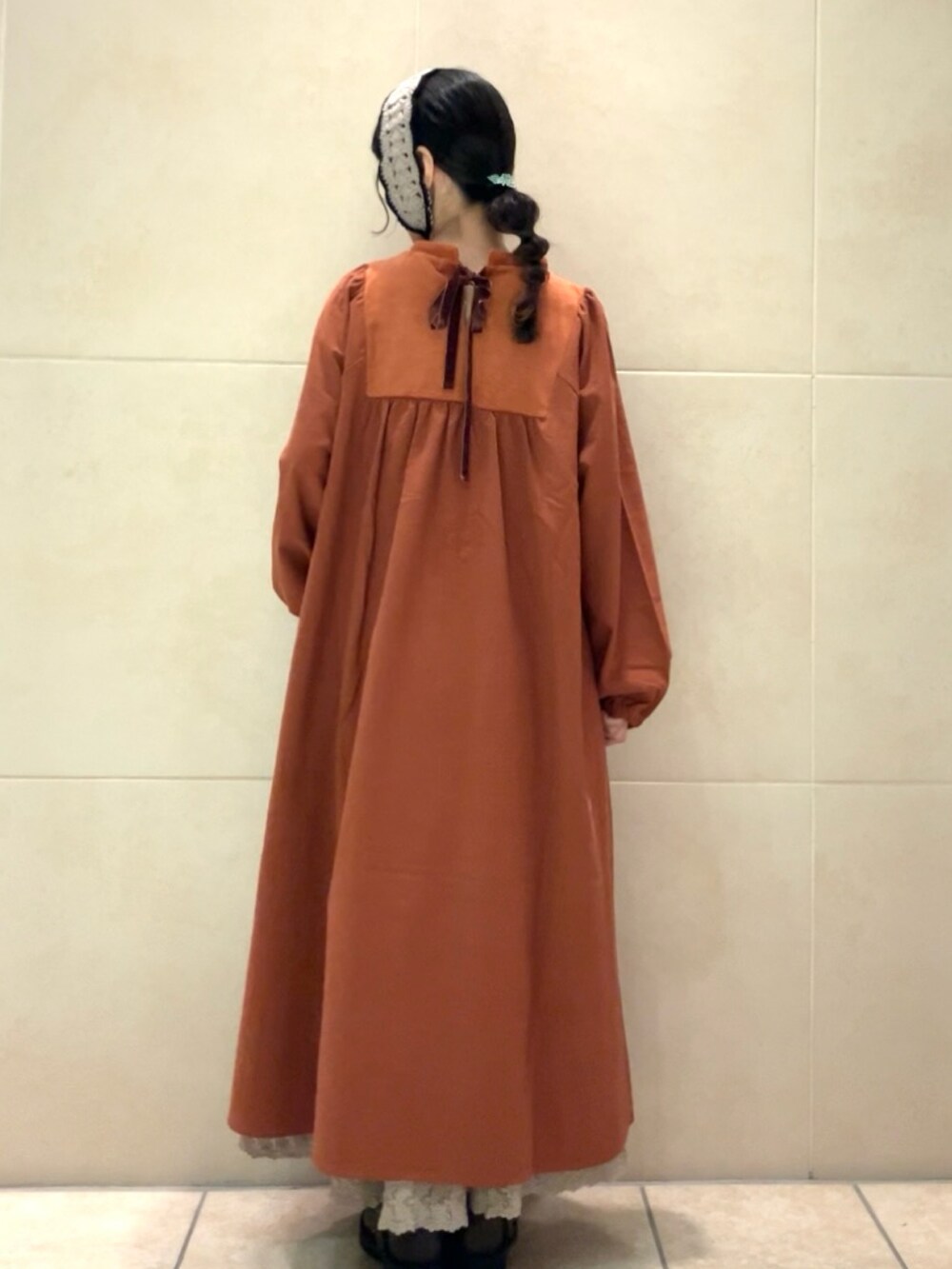 オレンジ系のワンピース、ブラウン系のブーツ、パープル系のヘアバンドを着用したレディースの秋コーディネートの2枚目の写真