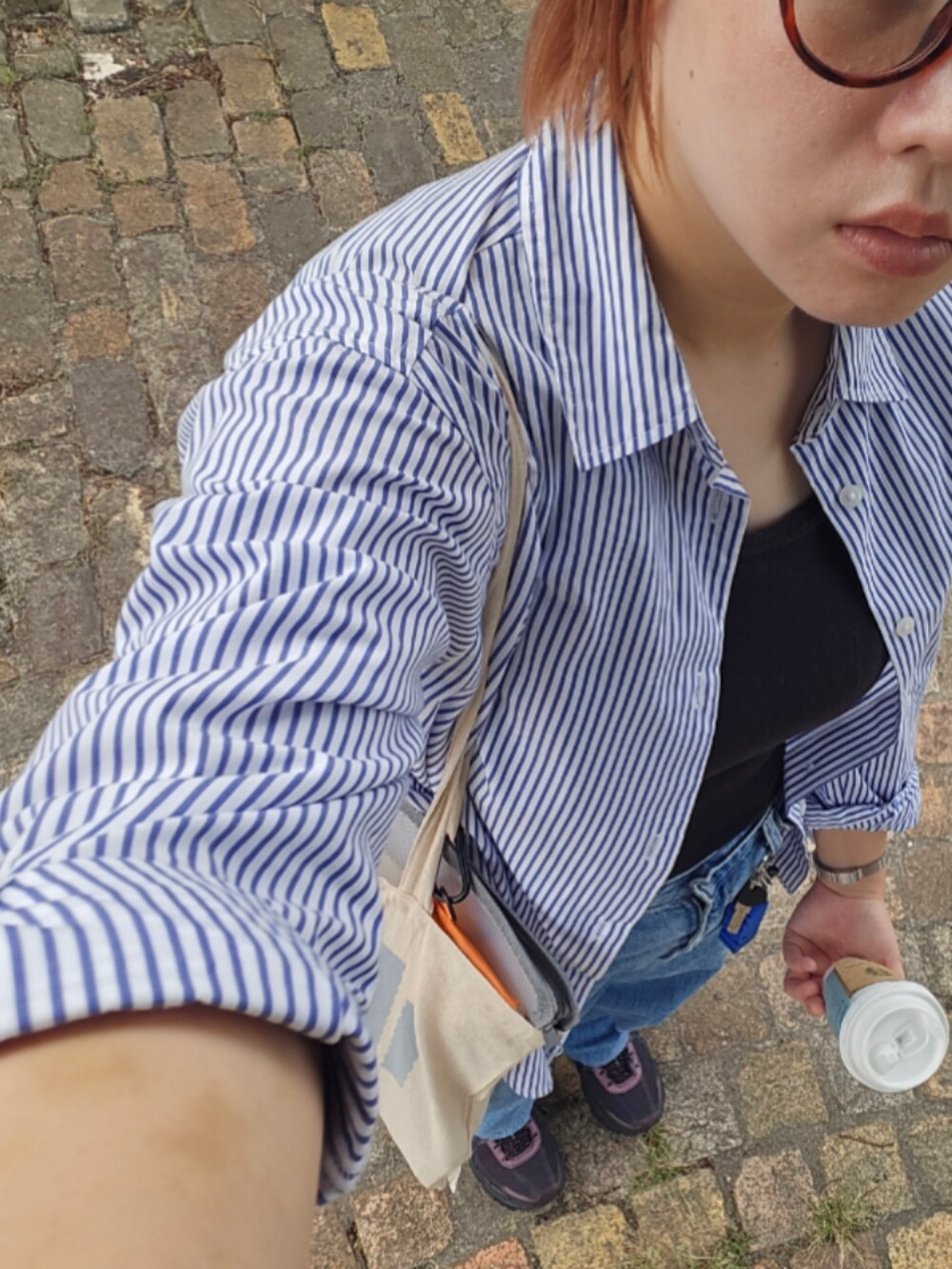 ブルー系のデニムパンツ、レッド系のスニーカー、ブラック系のタンクトップを着用したレディースの秋コーディネートの2枚目の写真