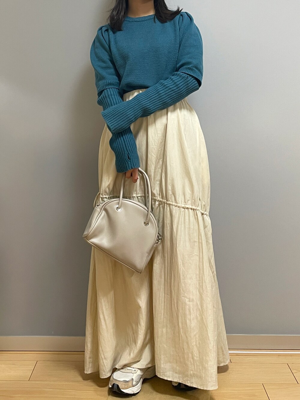 ブルー系のニット/セーター、ホワイト系のスカート、ホワイト系のボストンバッグを着用したレディースの冬コーディネートの2枚目の写真