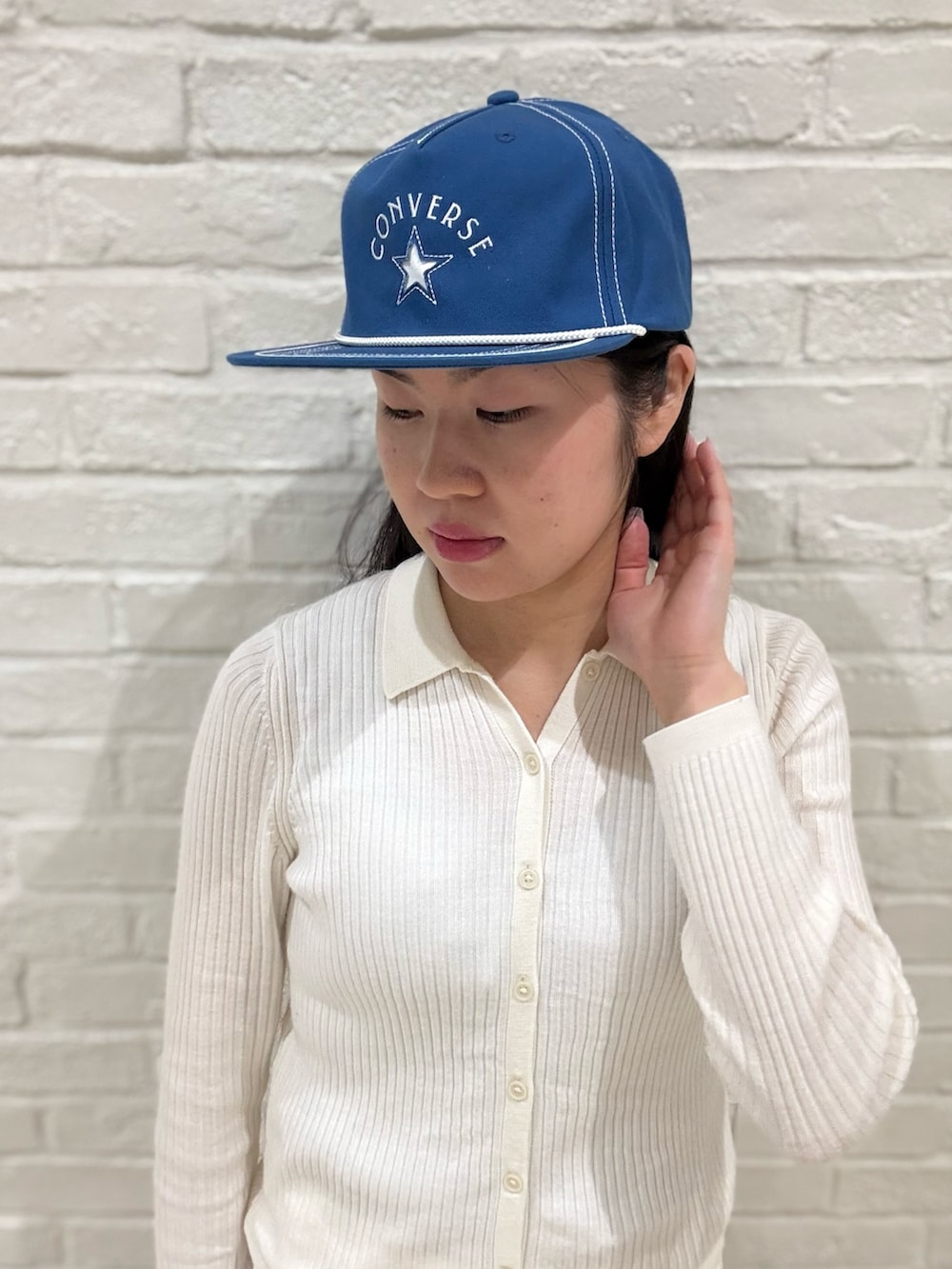 ホワイト系のニット/セーター、ホワイト系のデニムパンツ、ブラック系のブーツを着用したレディースの夏コーディネートの2枚目の写真