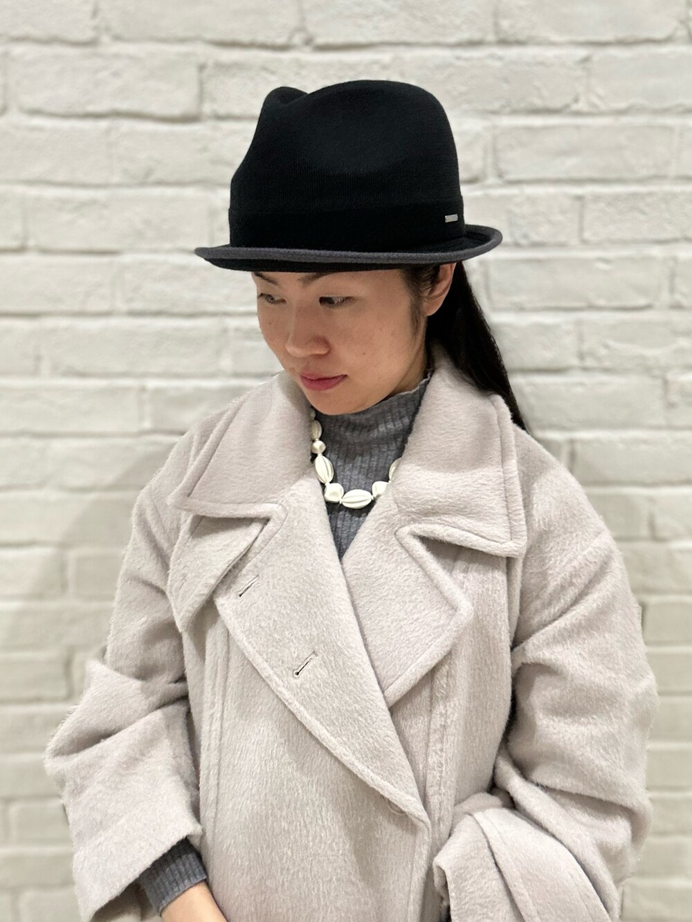 グレー系のニット/セーター、ベージュ系のステンカラーコート、ブラック系のスニーカーを着用したレディースの冬コーディネートの5枚目の写真