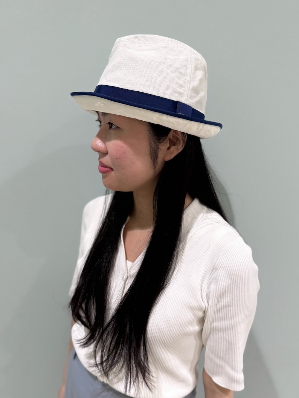 ホワイト系のニット/セーター、ブルー系のスラックス、ブルー系のスニーカーを着用したレディースの夏コーディネートの2枚目の写真