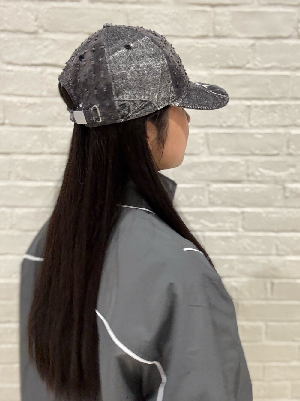 グレー系のマウンテンパーカー、ホワイト系のデニムパンツ、ブラック系のローファーを着用したレディースの夏コーディネートの3枚目の写真