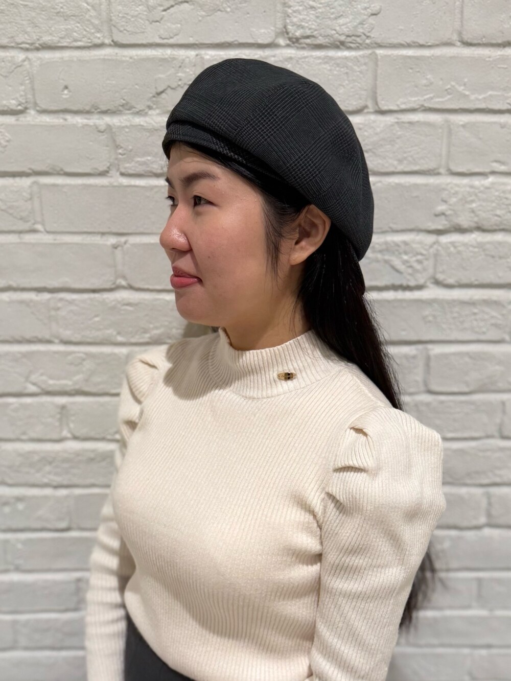 ベージュ系のニット/セーター、グレー系のスカート、ブラック系のブーツを着用したレディースの冬コーディネートの6枚目の写真