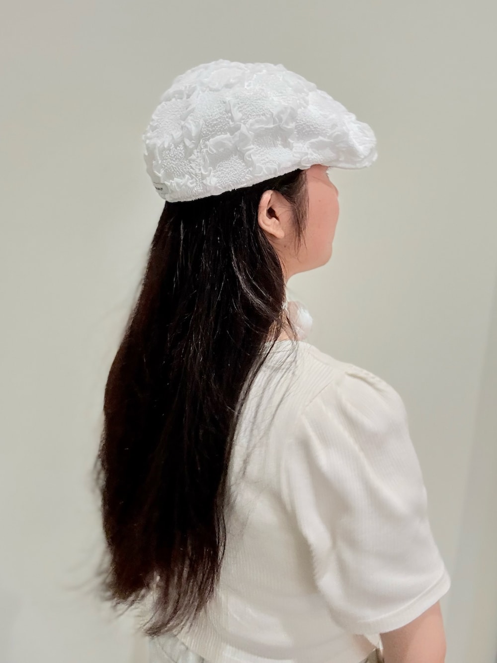 グレー系のスニーカー、ホワイト系のアンサンブル、ブルー系のデニムパンツを着用したレディースの夏コーディネートの3枚目の写真