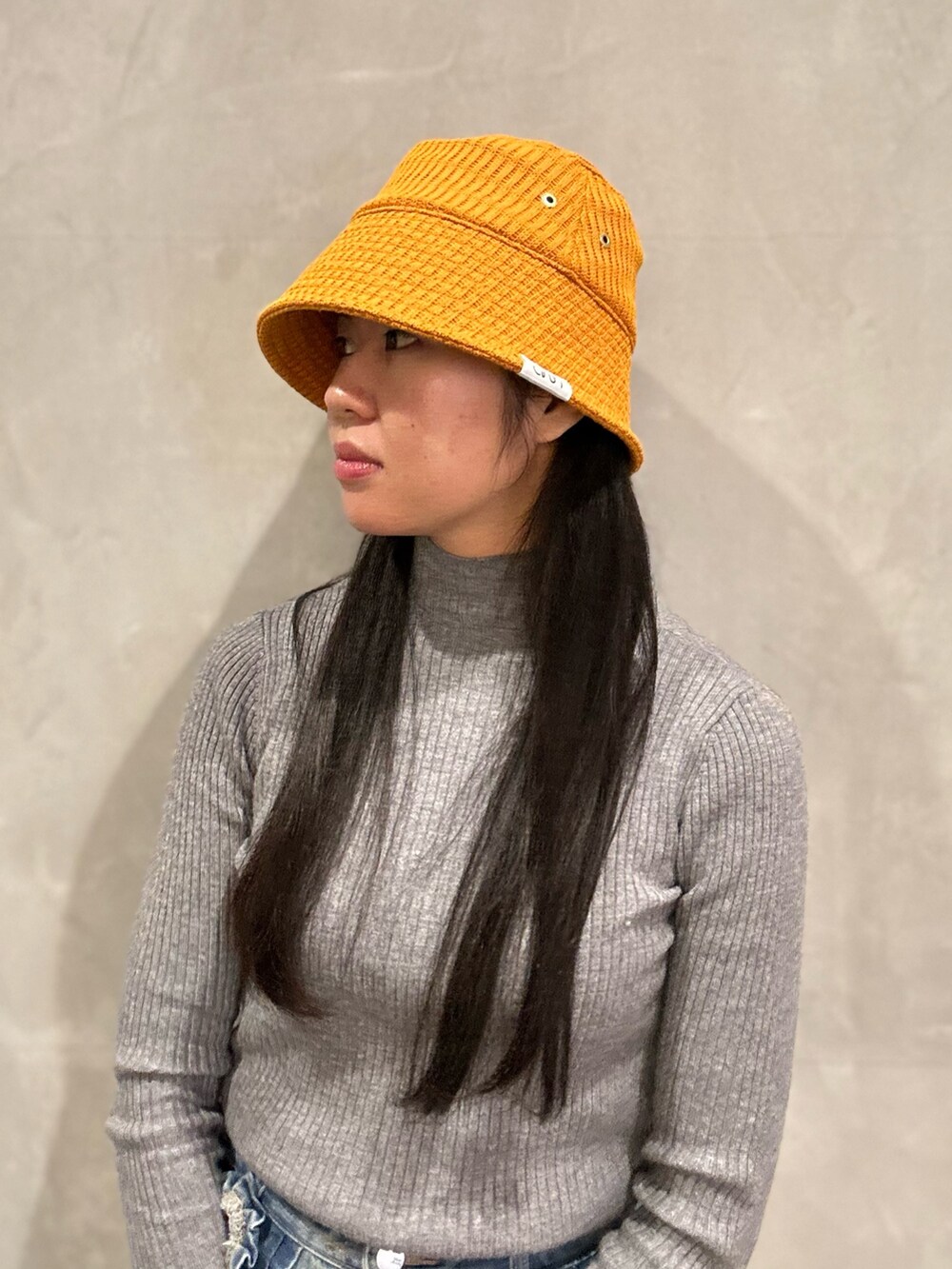 グレー系のニット/セーター、ブルー系のデニムパンツ、ブラック系のスニーカーを着用したレディースの冬コーディネートの2枚目の写真