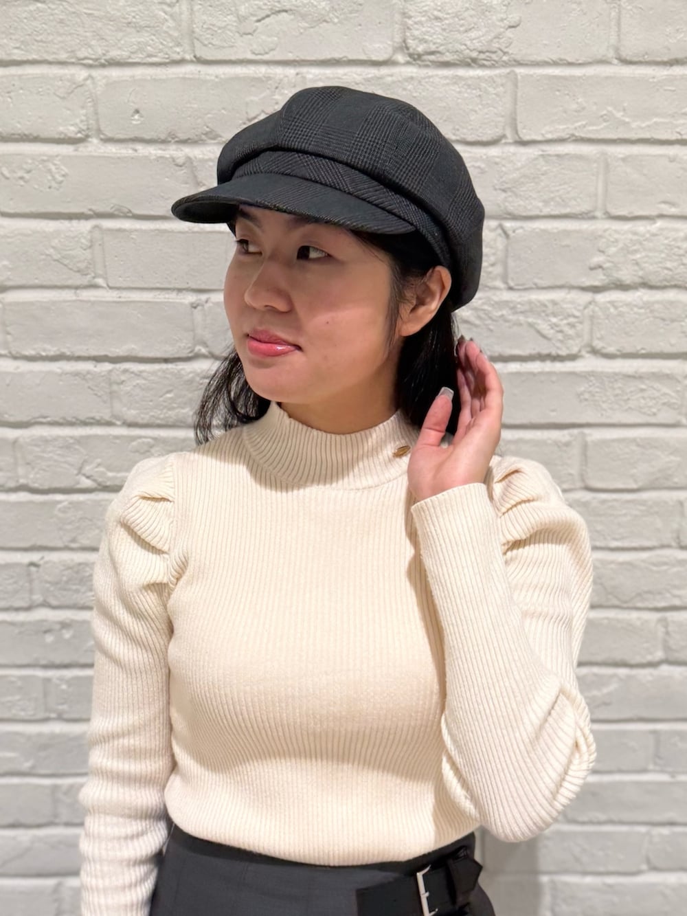 ベージュ系のニット/セーター、グレー系のスカート、ブラック系のブーツを着用したレディースの冬コーディネートの2枚目の写真