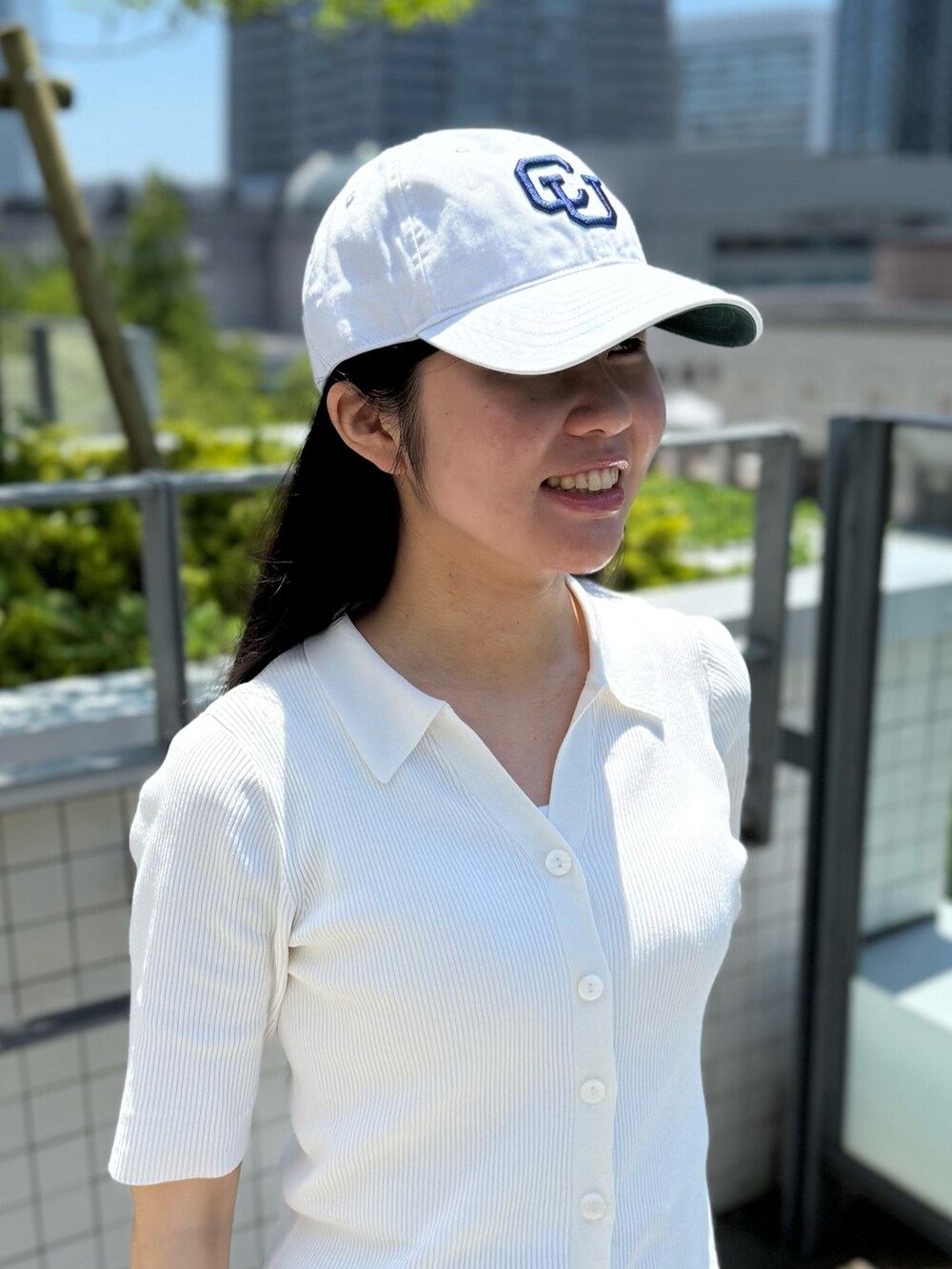 ホワイト系のニット/セーター、グレー系のスラックス、グレー系のスニーカーを着用したレディースの夏コーディネートの2枚目の写真