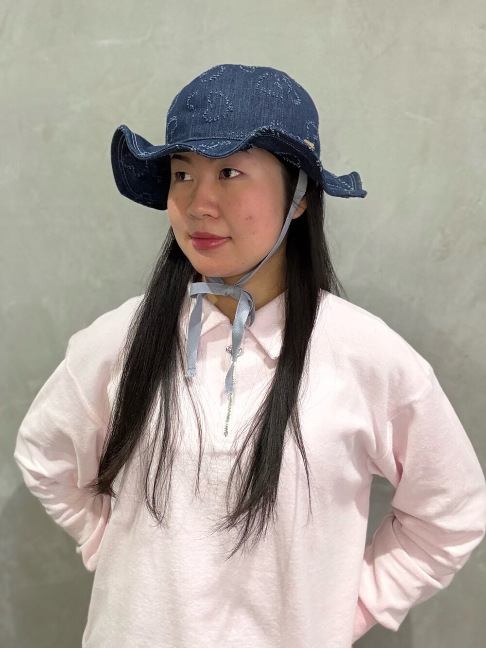 ピンク系のスウェット、ブルー系のデニムパンツ、グレー系のスニーカーを着用したレディースの春コーディネートの2枚目の写真