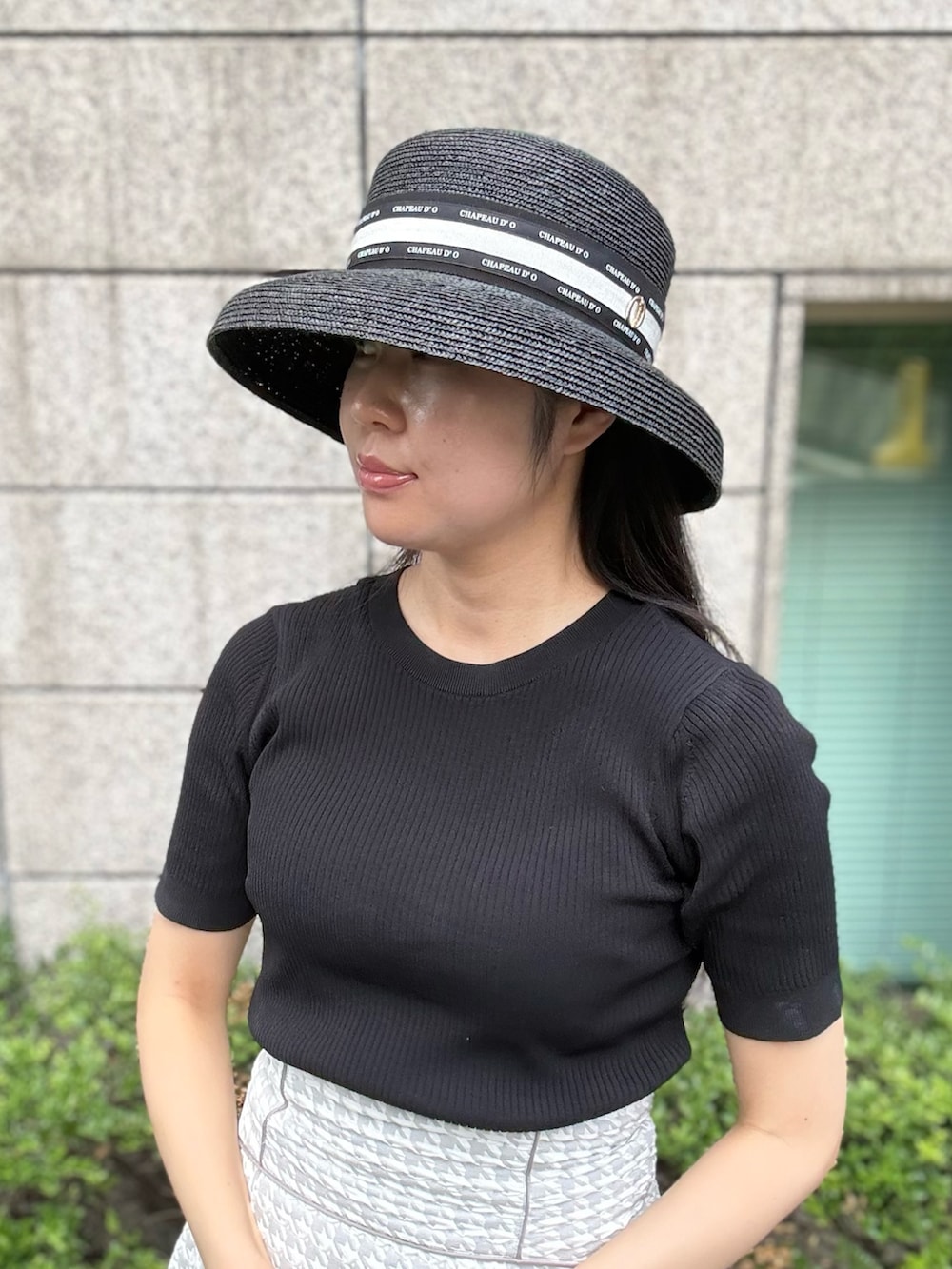 グレー系のスカート、シルバー系のスニーカー、ブラック系のニット/セーターを着用したレディースの夏コーディネートの2枚目の写真