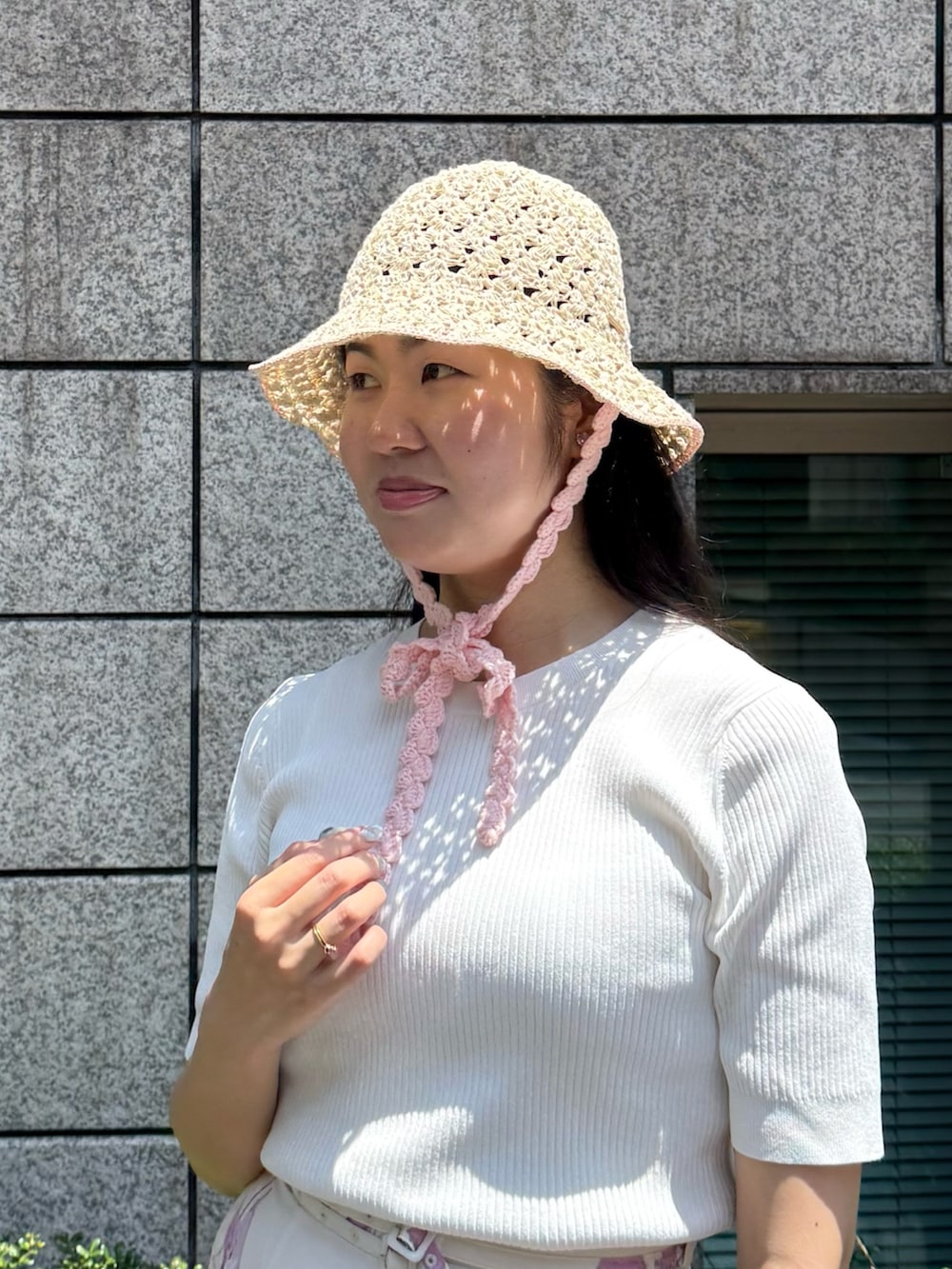 ホワイト系のニット/セーター、ピンク系のスカート、ホワイト系のシューズを着用したレディースの夏コーディネートの2枚目の写真