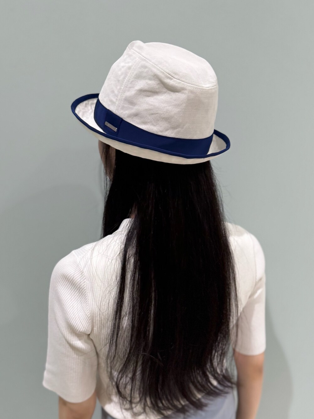 ホワイト系のニット/セーター、ブルー系のスラックス、ブルー系のスニーカーを着用したレディースの夏コーディネートの3枚目の写真