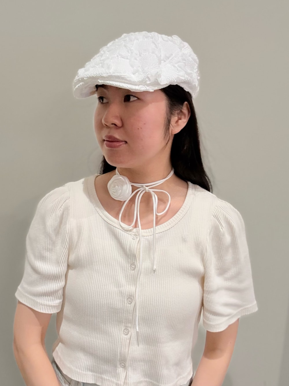 グレー系のスニーカー、ホワイト系のアンサンブル、ブルー系のデニムパンツを着用したレディースの夏コーディネートの2枚目の写真