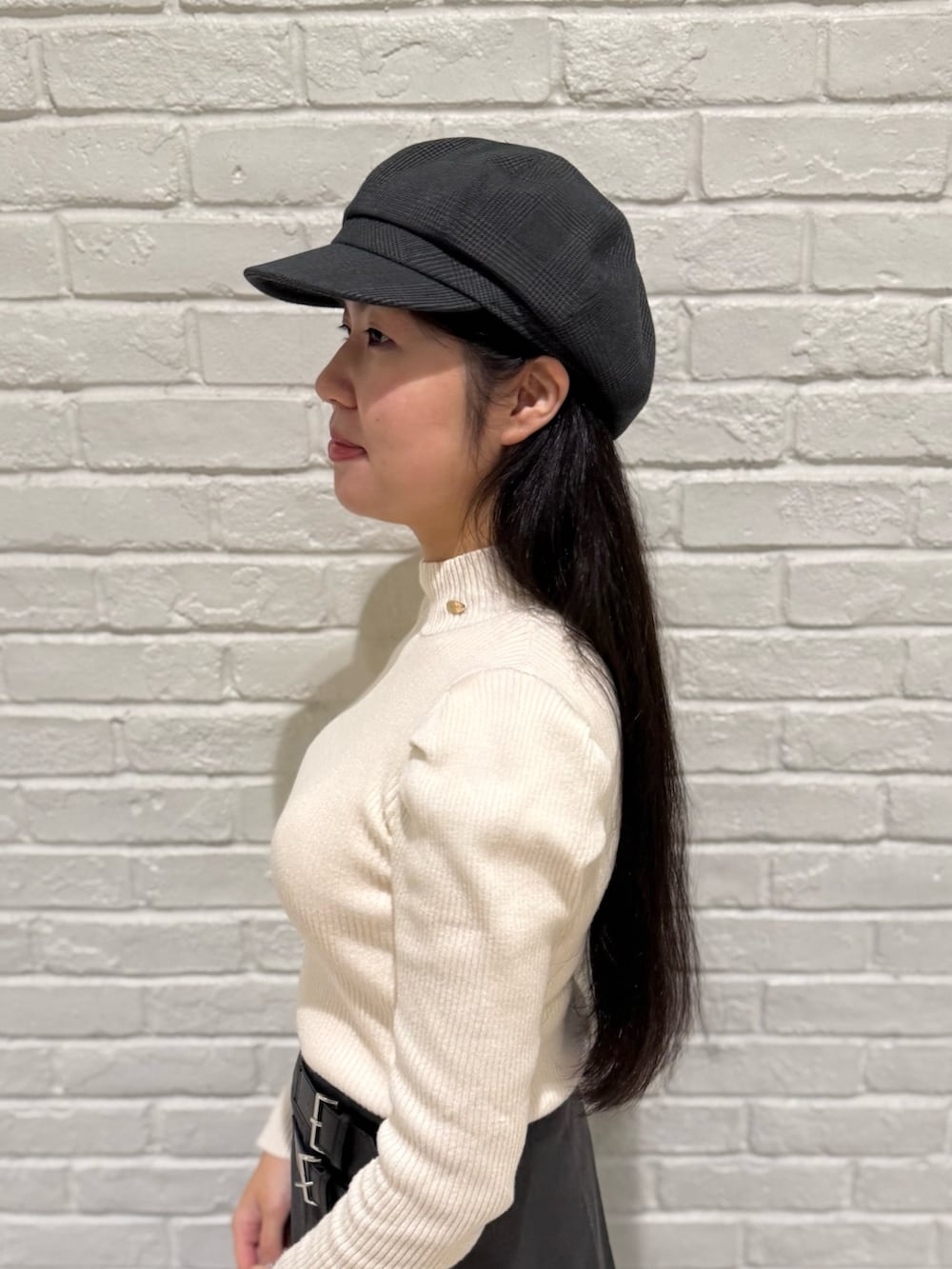 ベージュ系のニット/セーター、グレー系のスカート、ブラック系のブーツを着用したレディースの冬コーディネートの3枚目の写真