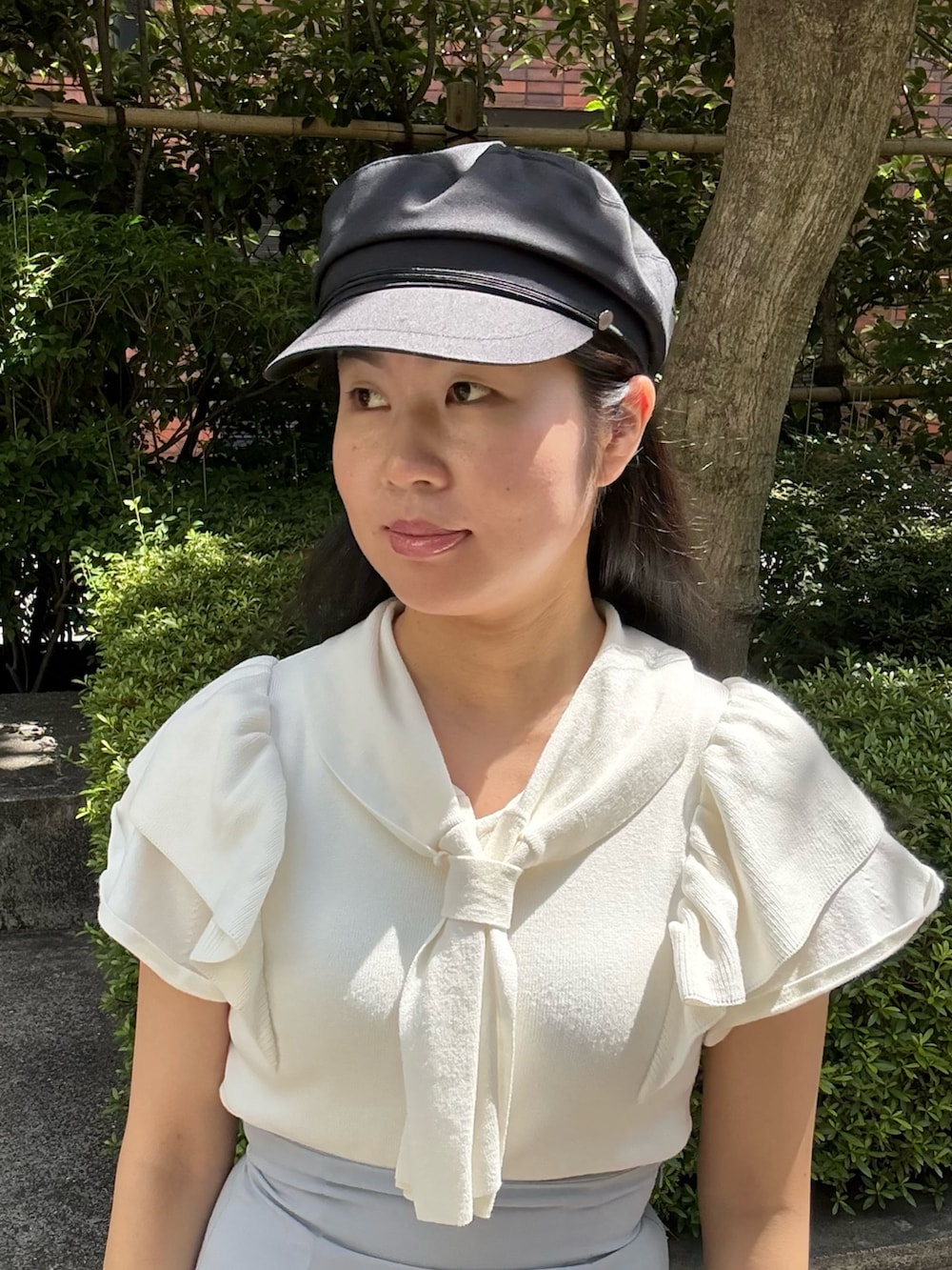 ホワイト系のニット/セーター、グレー系のスカート、ベージュ系のスニーカーを着用したレディースの夏コーディネートの2枚目の写真