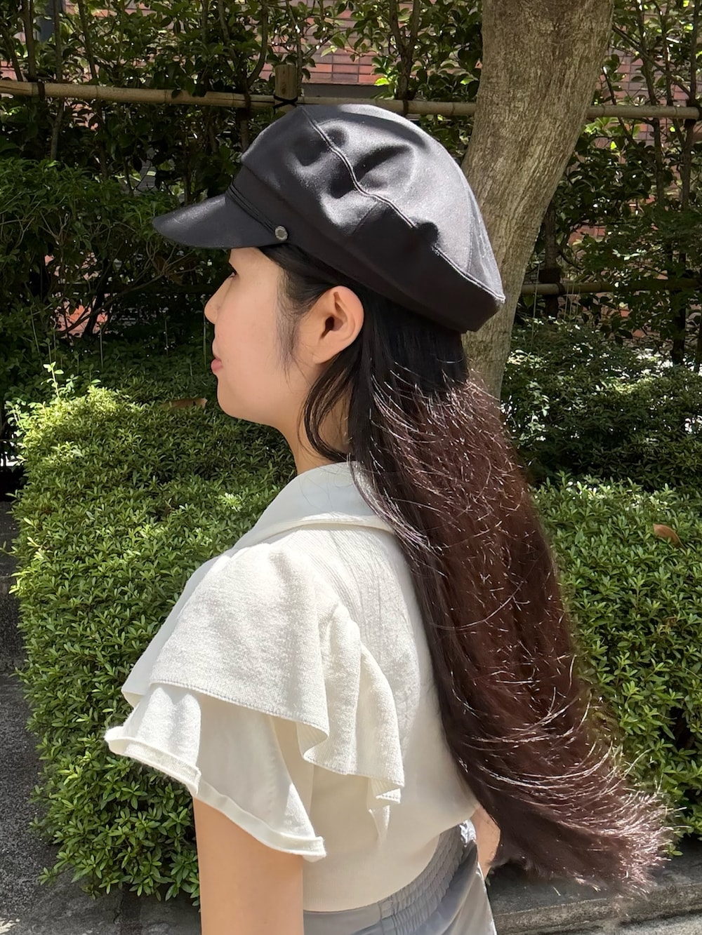 ホワイト系のニット/セーター、グレー系のスカート、ベージュ系のスニーカーを着用したレディースの夏コーディネートの3枚目の写真