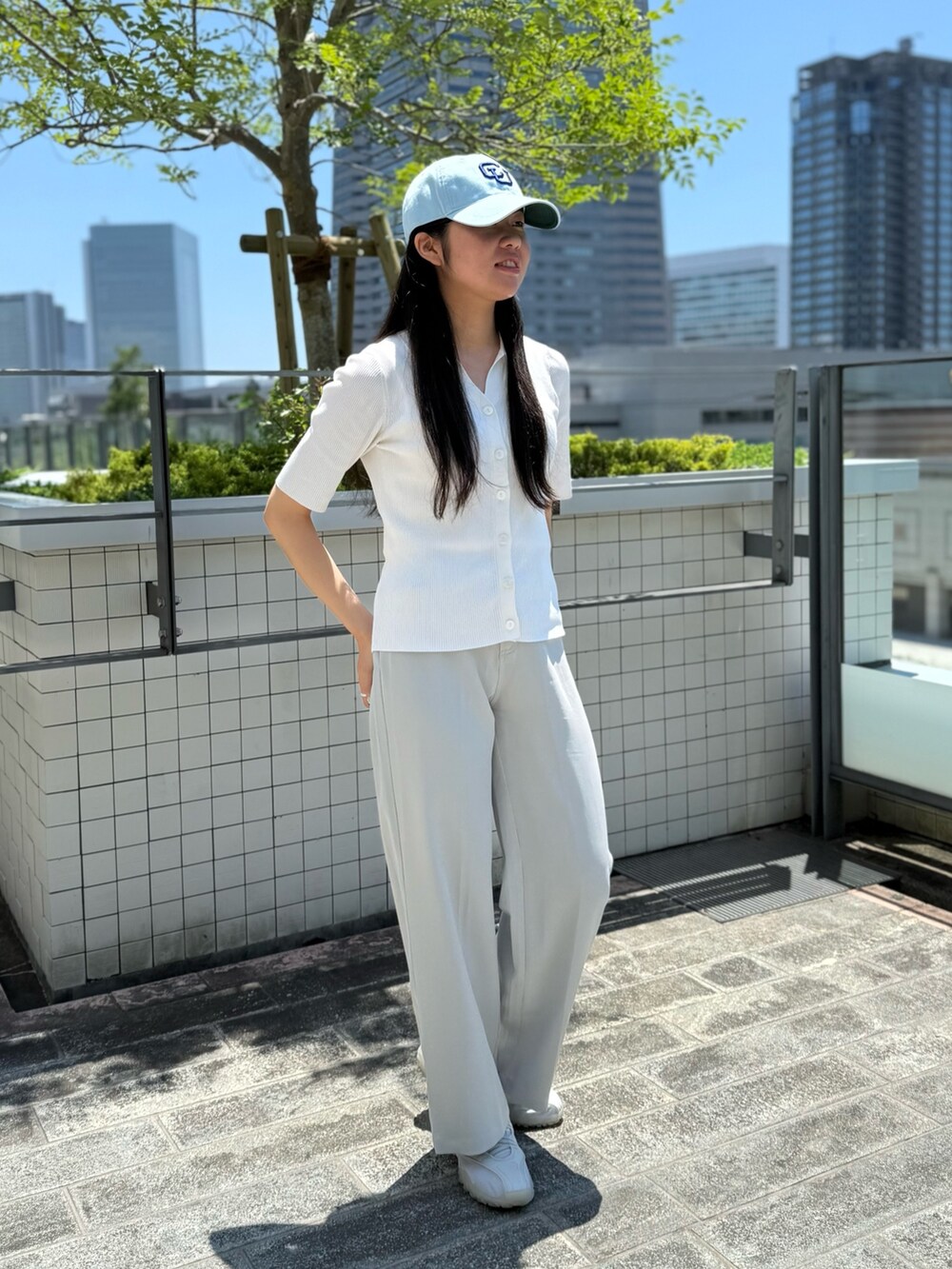 ホワイト系のニット/セーター、グレー系のスラックス、グレー系のスニーカーを着用したレディースの夏コーディネートの4枚目の写真