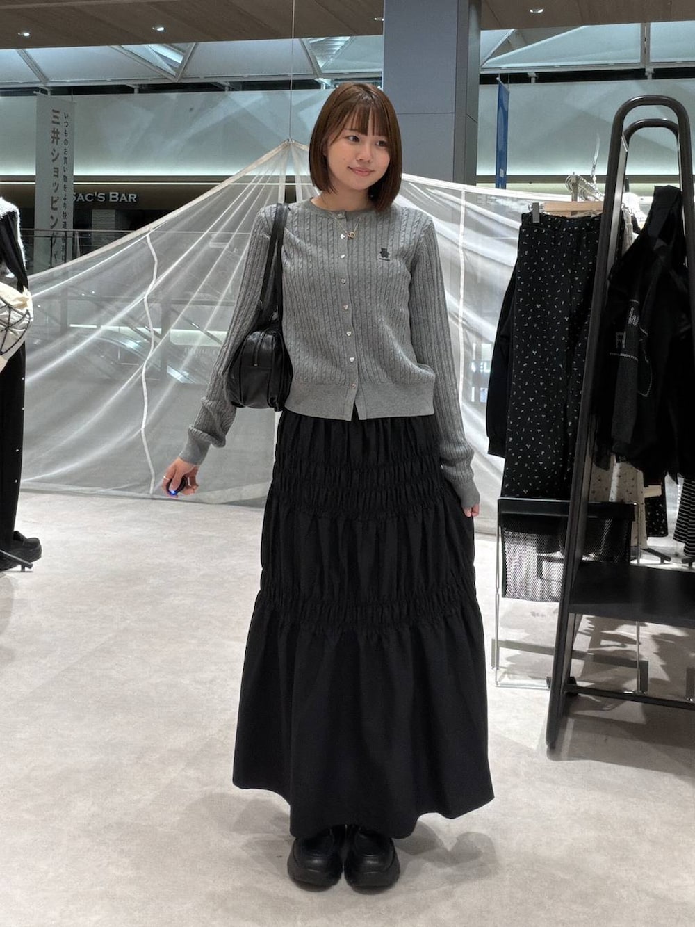 グレー系のカーディガン/ボレロ、ブラック系のボストンバッグ、ブラック系のスカートを着用したレディースの秋コーディネートの4枚目の写真