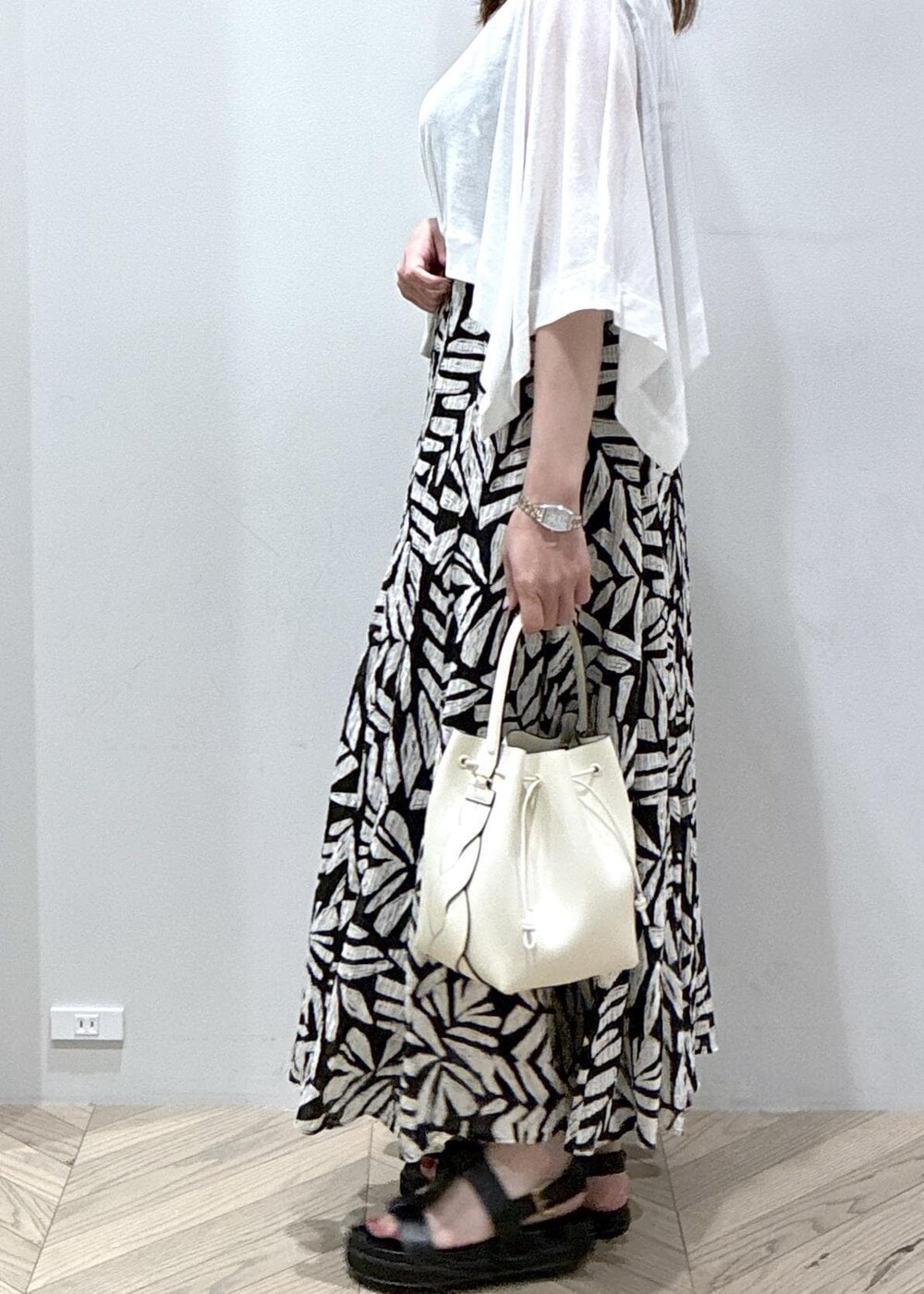 ブラック系のワンピース、ホワイト系のTシャツ/カットソー、ホワイト系のショルダーバッグを着用したレディースの夏コーディネートの2枚目の写真