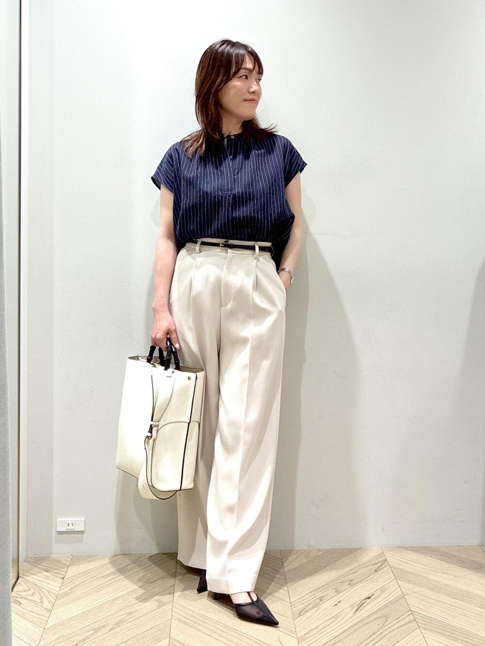 ホワイト系のトートバッグ、ブラック系のパンプス、ベージュ系のその他パンツを着用したレディースの夏コーディネートの2枚目の写真