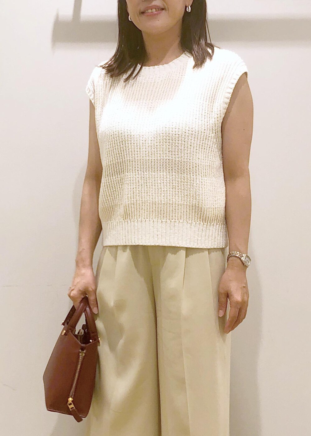 ホワイト系のサンダル、レッド系のハンドバッグ、ホワイト系のベストを着用したレディースの夏コーディネートの6枚目の写真