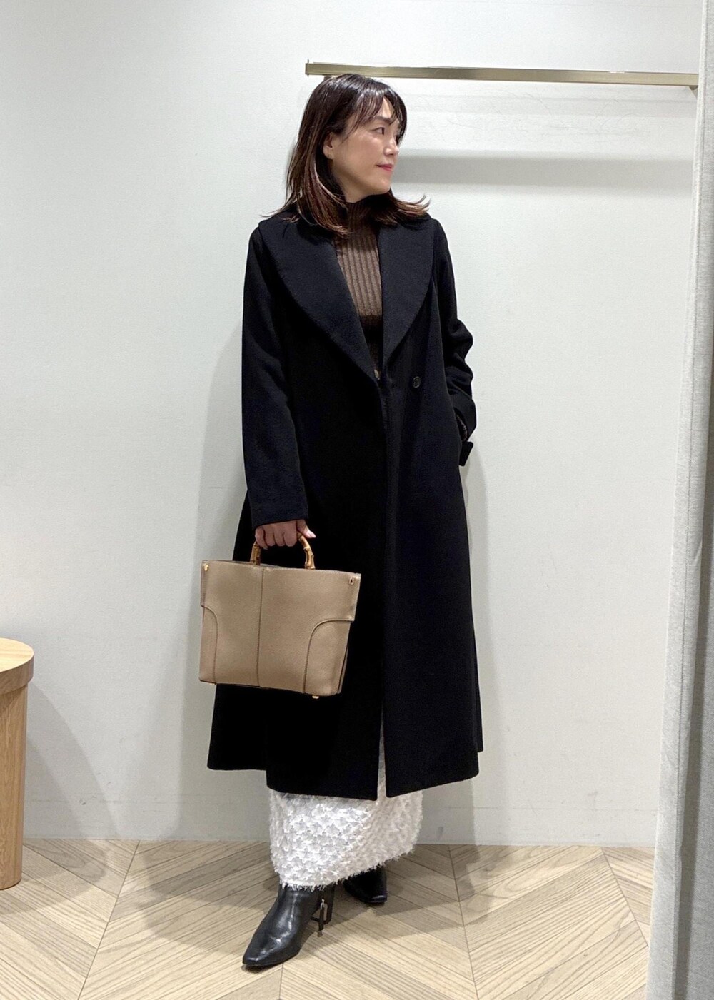 ブラック系のブーツ、シルバー系のスカート、ブラウン系のニット/セーターを着用したレディースの冬コーディネートの2枚目の写真