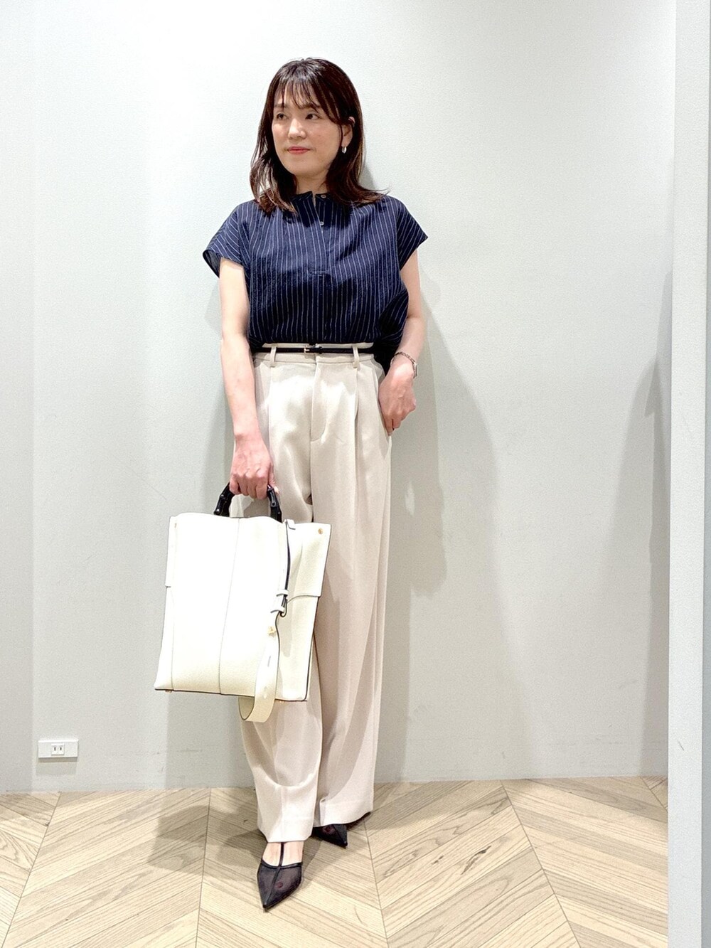 ホワイト系のトートバッグ、ブラック系のパンプス、ベージュ系のその他パンツを着用したレディースの夏コーディネートの3枚目の写真