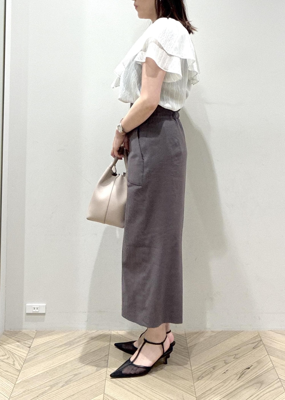 ブラック系のパンプス、グレー系のスカート、ホワイト系のシャツ/ブラウスを着用したレディースの夏コーディネートの5枚目の写真