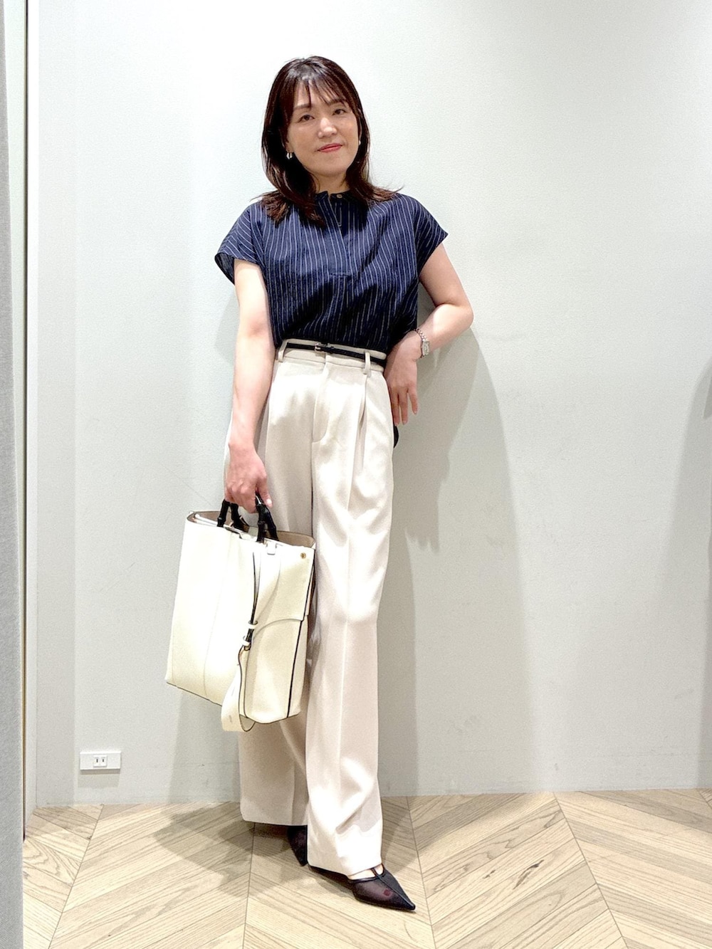 ホワイト系のトートバッグ、ブラック系のパンプス、ベージュ系のその他パンツを着用したレディースの夏コーディネートの9枚目の写真