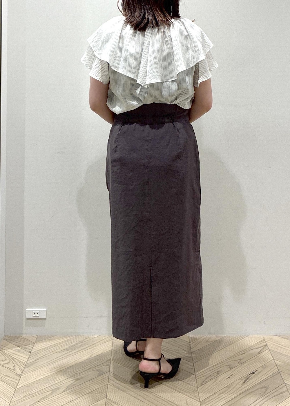 ブラック系のパンプス、グレー系のスカート、ホワイト系のシャツ/ブラウスを着用したレディースの夏コーディネートの7枚目の写真