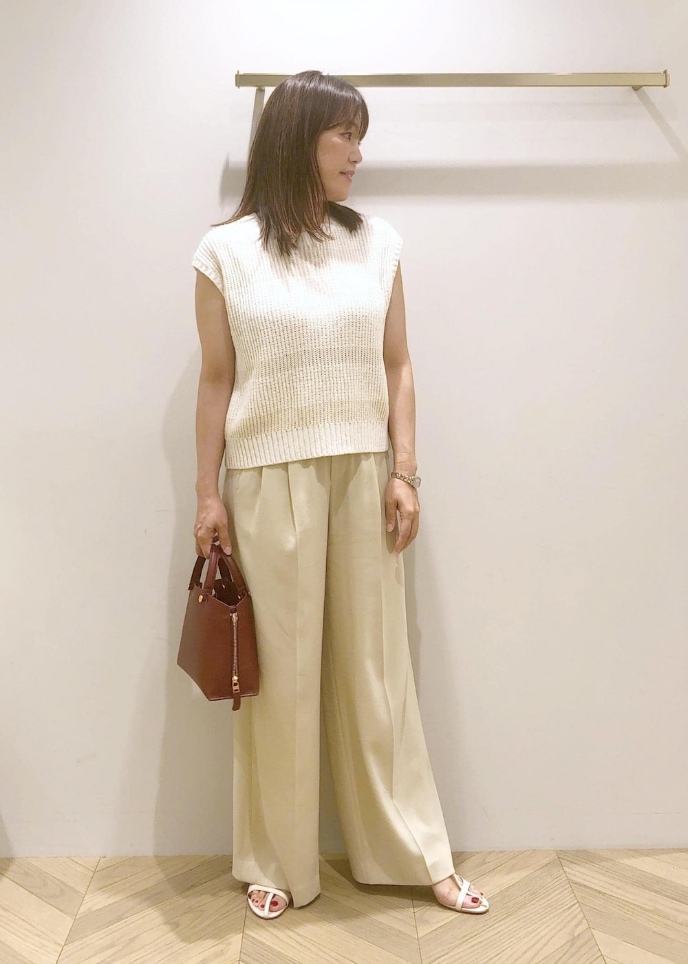 ホワイト系のサンダル、レッド系のハンドバッグ、ホワイト系のベストを着用したレディースの夏コーディネートの2枚目の写真